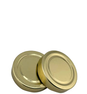Deux couvercles métalliques dorés twist-off pour bocaux en verre, fond blanc.